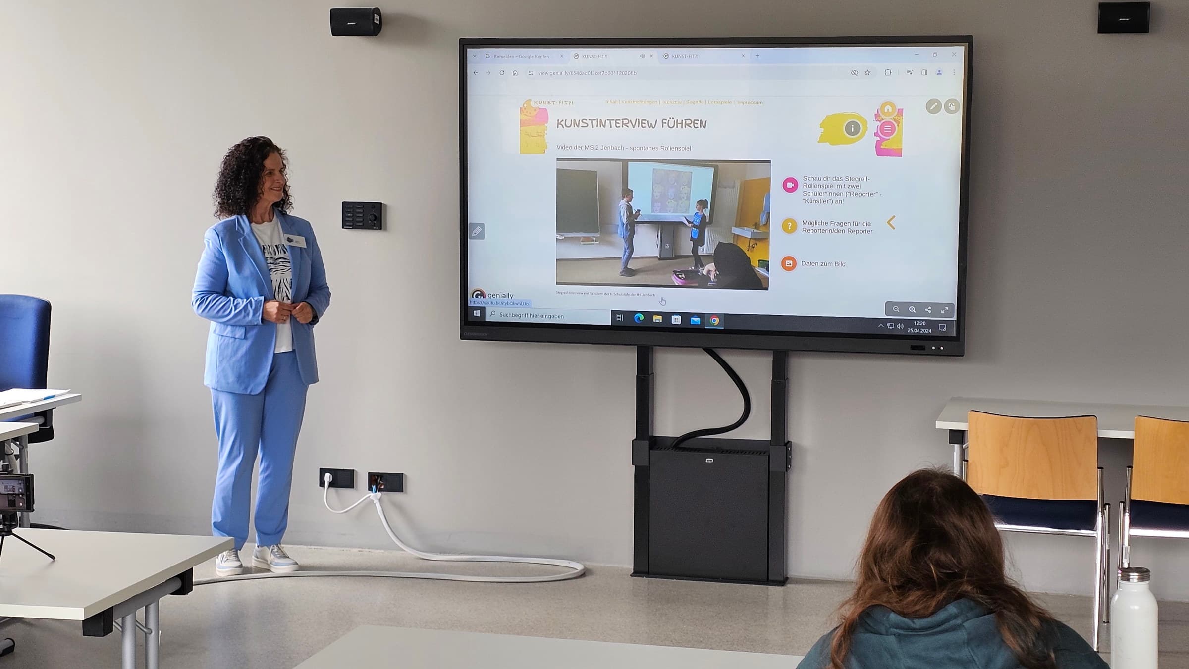 Einsatz des interaktiven MultiTouch-Displays von Clevertouch während des E-Future-Tags an der PHT, demonstriert durch eine Frau in einem blauen Anzug, die die Funktionen auf dem Bildschirm erklärt, während eine Person zuschaut.